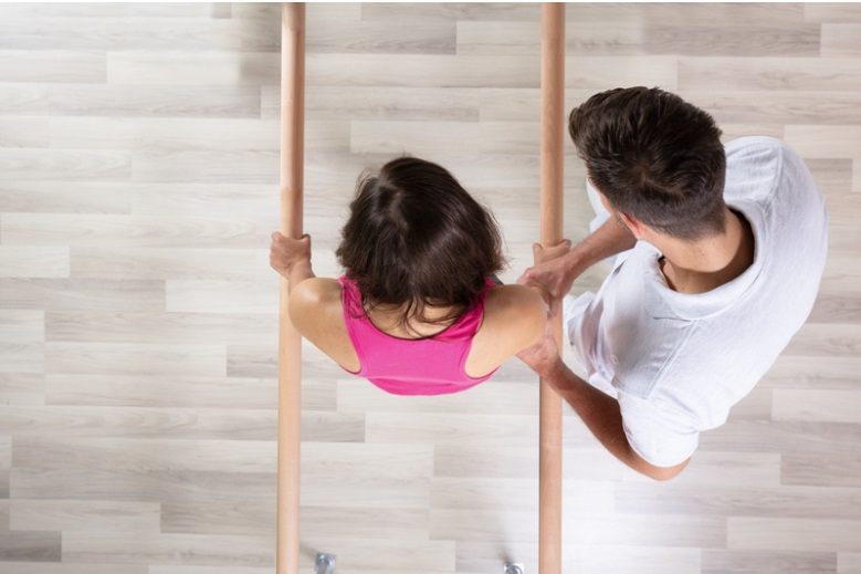 Man assisting a woman with physical exercise therapy.